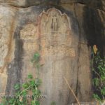 Carvinfs of a Tirthankar and inscription on a rock.