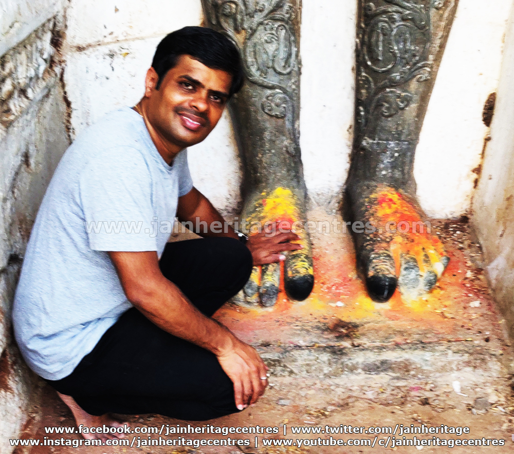 Researchers Nitin H P at the feet of Bahubali statue with inscription.